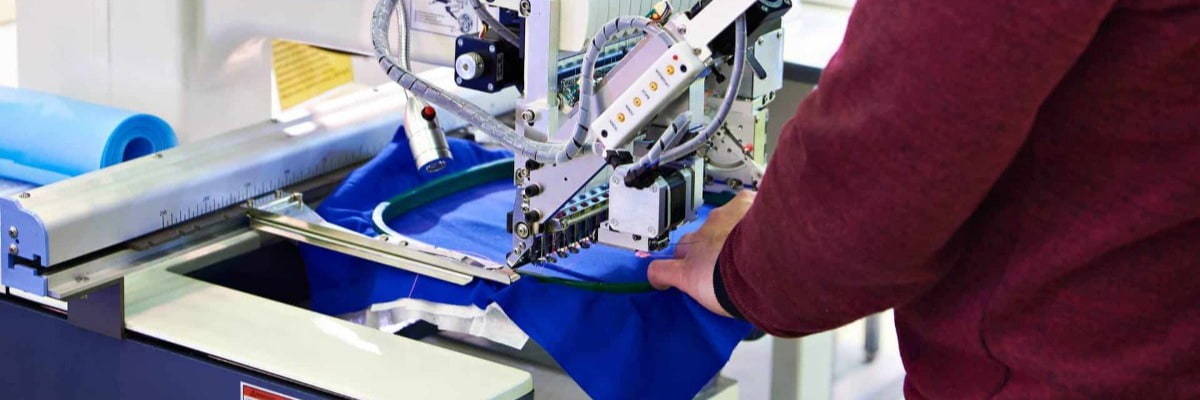 Working technician specialist embroidery industrial machine in sewing workshop